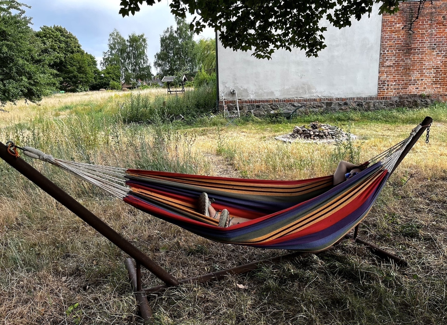 Eine Person entspannt in einer bunten Hängematte im Garten.