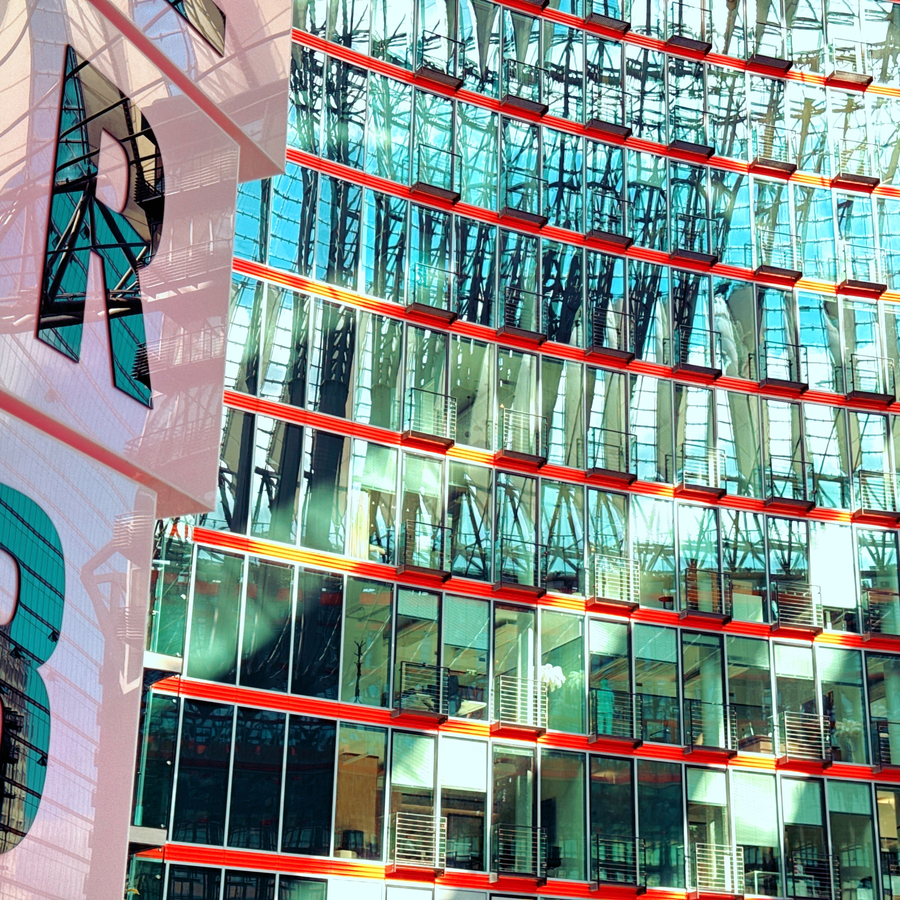 An einer Fassade eines modernen Glasgebäudes spiegelt sich das Innere eines anderen Gebäudes mit einer Stahlkonstruktion.
